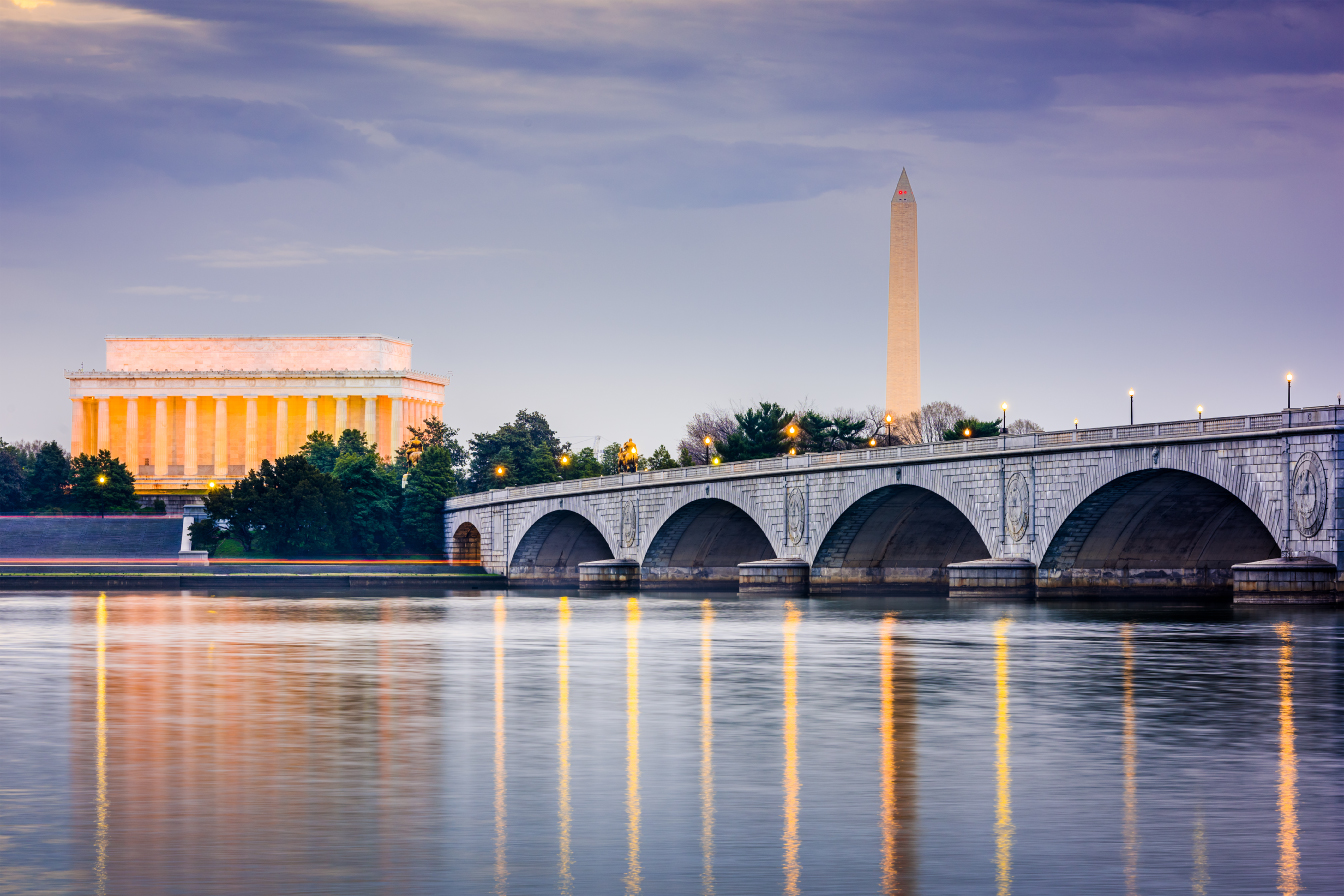 A bridge over the water with a large building in the background.